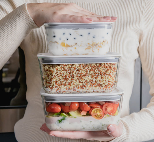 3 potes de vidro hermético com alimentos dentro sendo segurados um em cima do outro.