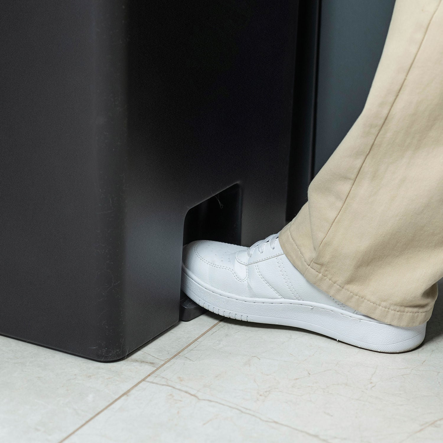 lixeira com pedal preta da Ou no chão sendo mostrada como usar o pedal